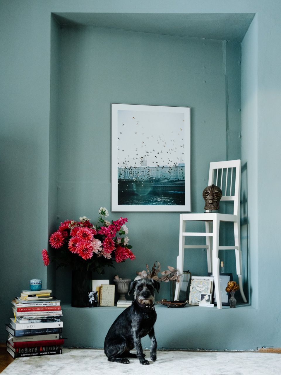 Gemütliche Wandnische in Oval Room Blue von Farrow & Ball mit Kunst, Büchern, Blumen und Hund im Wohnatelier Schloss Arenberg.