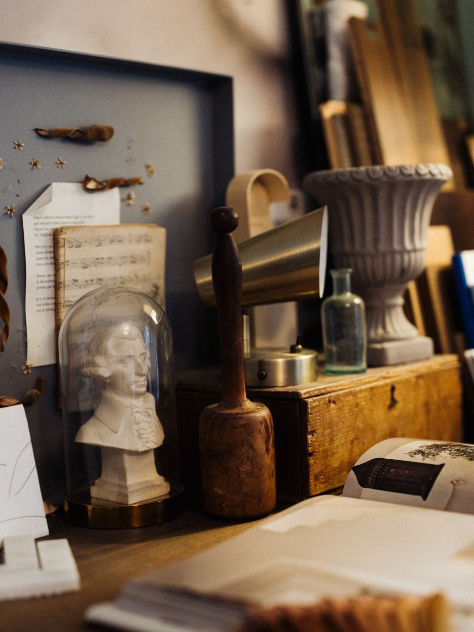 Persönliche Sammlung aus alten Büchern, kleinen Skulpturen, Glasgefässen und Fundstücken, arrangiert auf einer historischen Holzkommode.